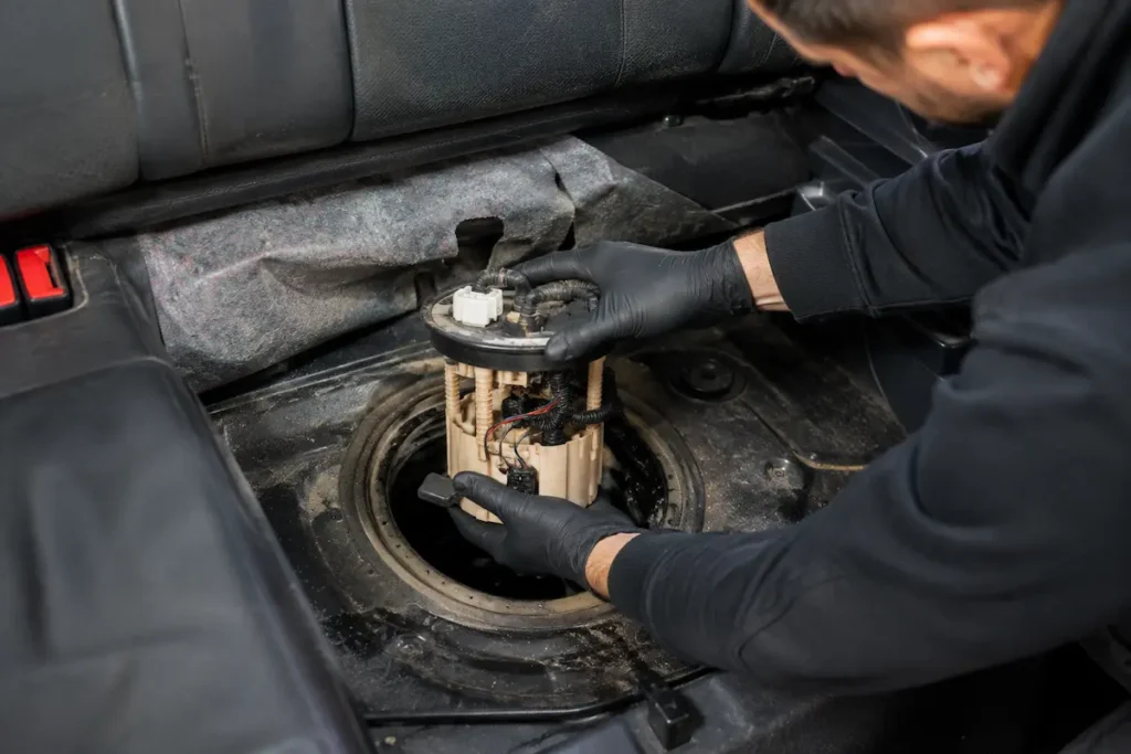 Mechanik wymienia moduł pompy paliwa znajdujący się pod tylną kanapą samochodu podczas profesjonalnej diagnostyki układu paliwowego.